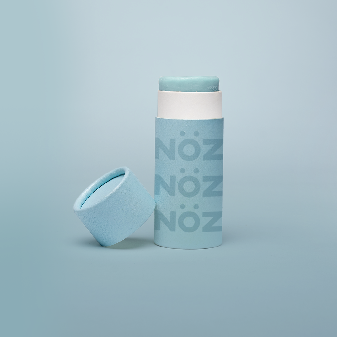 A single blue Nöz sunscreen stick in front of a blue background.