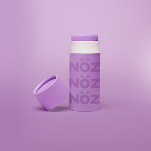 A single purple Nöz sunscreen stick in front of a purple background.