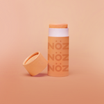 Load image into Gallery viewer, A single orange Nöz sunscreen stick in front of an orange background.
