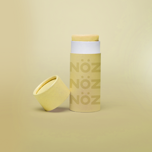 A single yellow Nöz sunscreen stick in front of a yellow background.