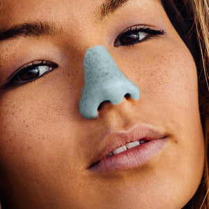 Headshot of a woman wearing blue Nöz sunscreen on her nose. 